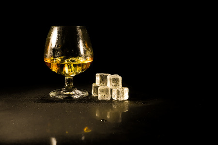 Whiskey in glass and ice on a black background.