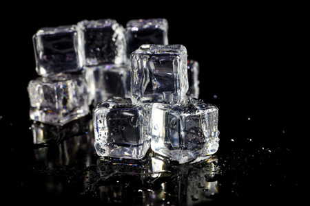 ice cubes reflection on black table background.