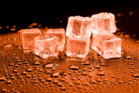 Water drop with ice cubes on lighting red background.の写真素材