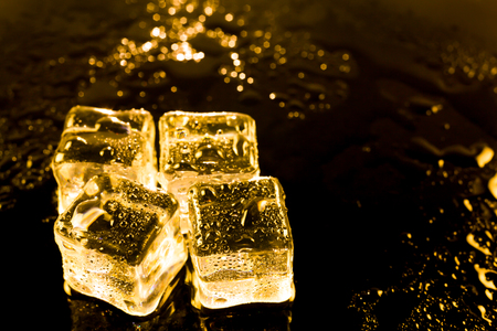 ice cubes and water drop on light golden background.の写真素材