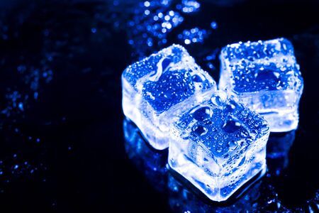 Blue ice cubes on black wet table.の写真素材
