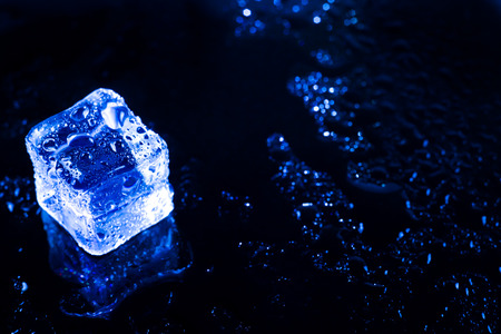 Blue ice cubes on black wet table.の写真素材