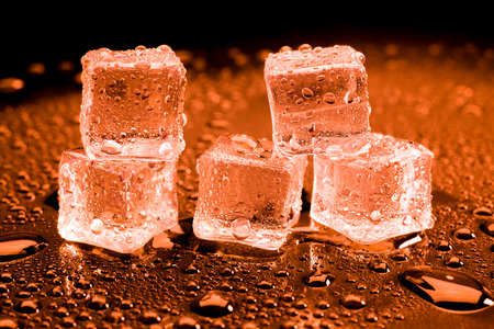 Water drop with ice cubes on lighting red background.の写真素材