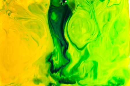 Yellow and green oil paint on water abstract background.