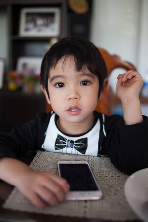 Little boy in Tuxedo clothes playing on smartphone.