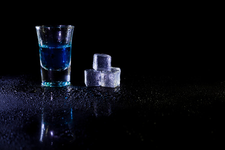 Cocktail blue shots with ice cubes on black background.の写真素材
