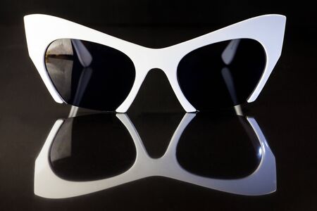 White fashion sunglasses on a black background.の写真素材
