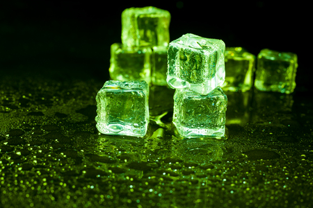 Green ice cubes on black background.の写真素材