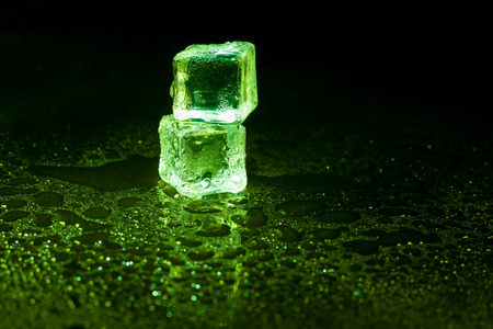 Green ice cubes on black background.の写真素材