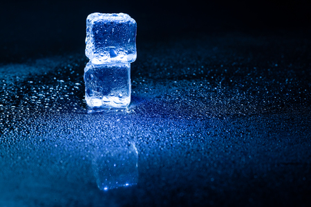 Blue ice cubes reflection on black table.の写真素材