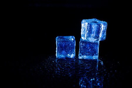 Blue ice cubes reflection on black table background.の写真素材