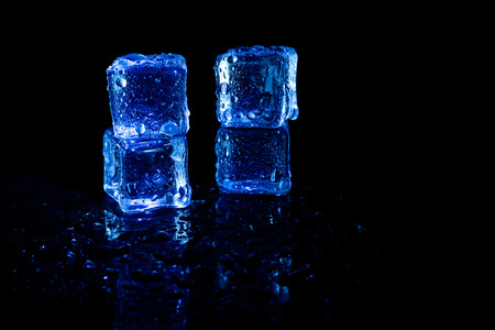Blue ice cubes reflection on black table background.の写真素材