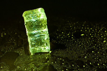 Green ice cubes on black table background.の写真素材