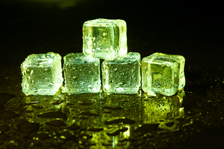 Green ice cubes on black table background.の写真素材