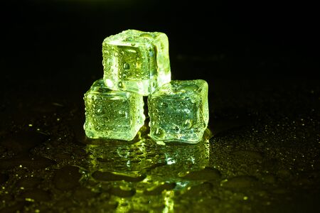 Green ice cubes on black table background.の写真素材