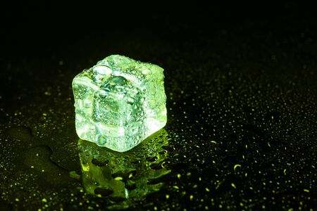 Green ice cubes on black table background.の写真素材