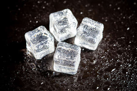 ice cubes reflection on black table background.