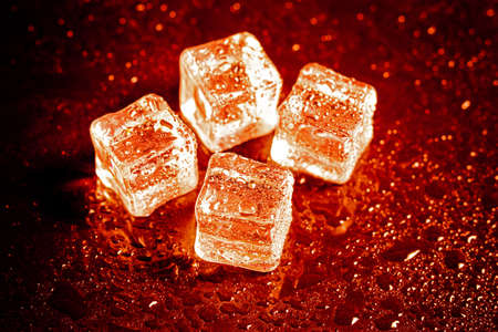 Red ice cubes reflection on black table background.