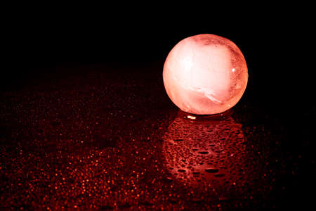 Red ice ball reflection on black background.の写真素材