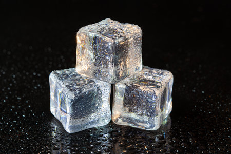 ice cubes reflection on black table background.