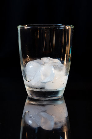 ice in whisky glass on a black table.の写真素材