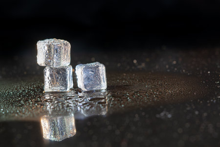 ice cubes reflection on black table background.