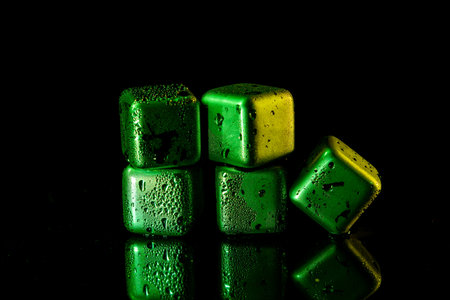 Green Stainless steel cubes simulating ice for cooling drinks on a black surface with a reflection.の写真素材