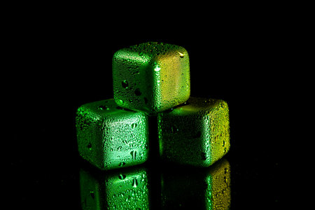 Green Stainless steel cubes simulating ice for cooling drinks on a black surface with a reflection.の写真素材