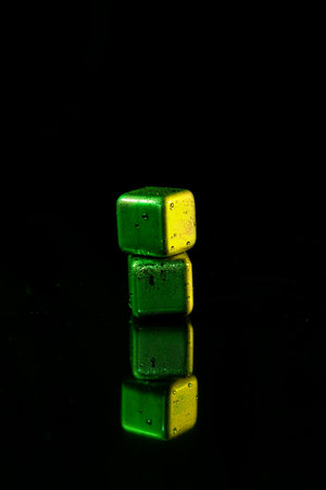 Green Stainless steel cubes simulating ice for cooling drinks on a black surface with a reflection.の写真素材