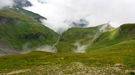 A cloud caught in a valley in Austrian Alpsの写真素材