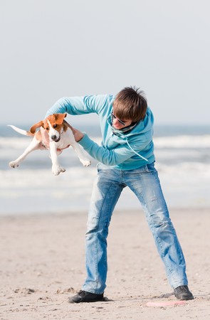 Young man playing with his beagle puppyの写真素材