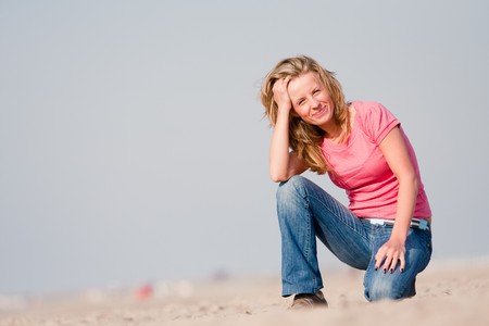 Young woman in pink t-shirt and jeans standing on sea shore. Sunset lightの写真素材