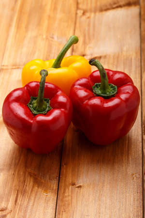Red and orange bell peppers on the wooden backgroundの写真素材