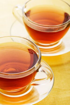 Two cups of tea on a yellow  wooden backgroundの写真素材