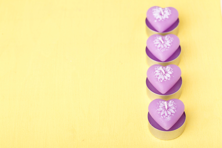 pink candles in the shape of heart closeup on the yellow backgroundの写真素材