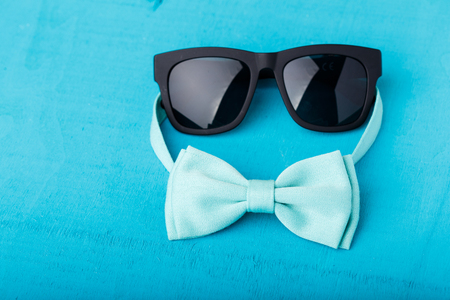 blue bow tie and sunglasses on blue wooden tableの写真素材
