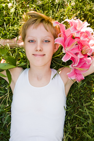 Beautiful girl laying in the grass with flowers in her hairの写真素材
