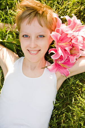 Beautiful girl laying in the grass with flowers in her hairの写真素材