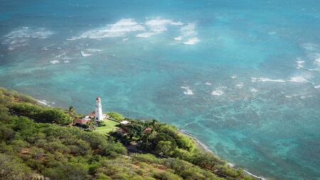 White lighthouse surrounded by azure ocean waters, shot at Diamond Head Lookout near Honolulu,...
