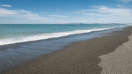 Coastal scenery with calm ocean and beach with blue sky backdrop. Shot at Napier Marine Parade in North Island of New Zealandの写真素材