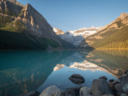 Beautiful alpine lake reflecting its surroundings, shot during sunrise at Lake Louise, Banff National Park, Canadaの写真素材