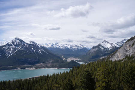 View on snowy mountain peaks and forest valley with lake, shot in Canadian Rockies at Prairie View Trail, Kananaskis, Alberta, Canadaの写真素材
