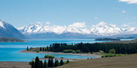 Vista with beautiful alpine scenery, turquoise glacier lake with snowy mountains in backdrop. Shot at Lake Tekapo, New Zealandの写真素材