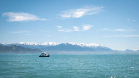 Boat on the ocean with mountain backdrop. Shot at Kaikoura peninsula, New Zealand