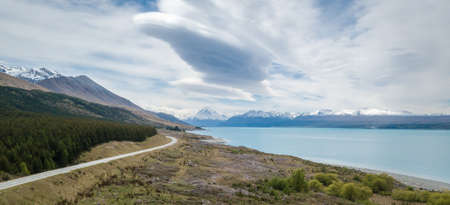 Alpine vista with turquoise lake and mountains in backdrop with highway leading towards them, shot at Aoraki Mt Cook National Park, New Zealandの写真素材