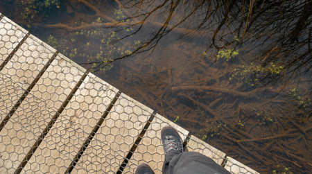 Diagonally split shot with wooden boardwalk and water reflections, looking down perspective. Shot...