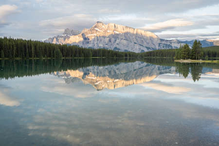 Peaceful colorful sunrise with dominant mountain reflecting on still lake s surface, Banff National Park, Canadaの写真素材