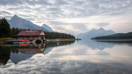 Peaceful sunrise on the bank of still alpine lake with boathouse, Jasper NP, Canadaの写真素材