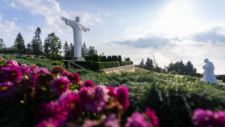 Statues of Jesus and pope forming religious monument surrounded by flowers, Slovakia, Europeの写真素材