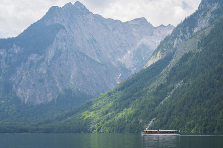 Small boat sailing on alpine lake surrounded by high mountains , Konigssee, Germanyの写真素材